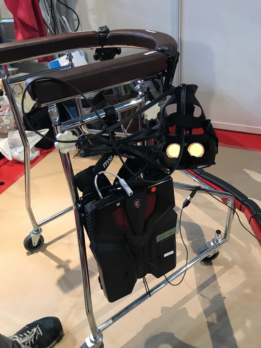 よく病院で使われるような歩行補助具につかまって自分の足で歩いていきます。VRヘッドセットとしてHTC Viveを採用。MSIのバックパック型PC「VR ONE」と接続しています