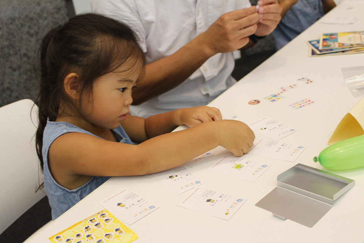 真剣な面持ちで名刺にデコレーションしています