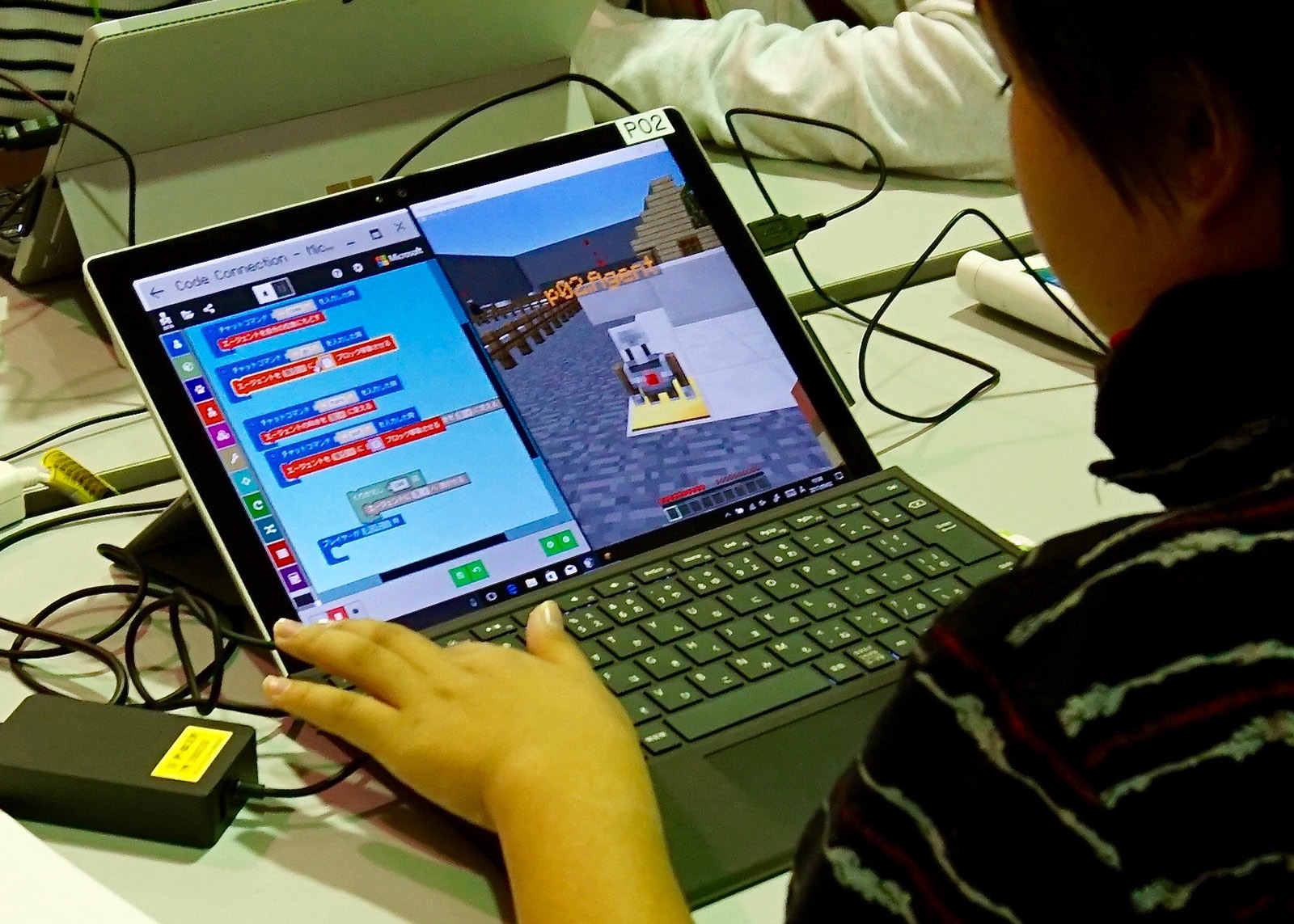 スクリーンの画面右が 「Minecraft:Education Edition」、画面左がプログラミングを行う「MakeCode」の画面