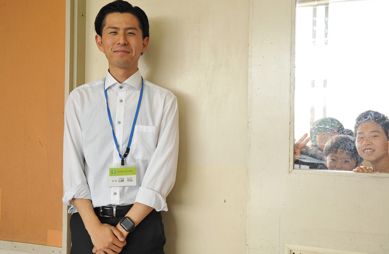 担任の山崎先生とひょっこり顔をのぞかせる児童たち