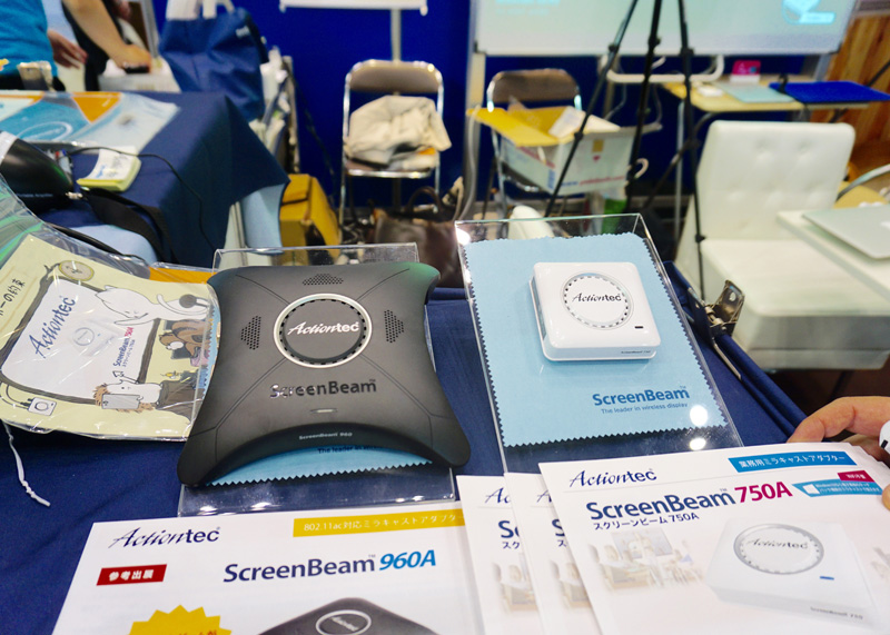 Actiontec ElectronicsブースではMiracastアダプター「<a href="https://www.screenbeam.com/ja/solutions/education-solutions/">ScreenBeam</a>」を展示（写真左）。ScreenBeam 960AはMacOSに対応しており、iOS対応に向けて準備中だという。 パソコンに表示された動画もディレイを感じることなく映写できる（写真右）