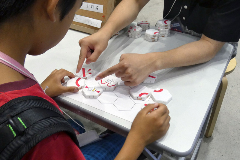 e-worksが展示していた「ぴらめきパズル」。六角形のピースの中にLEDや電池が入っており、正しく組み合わせると回路が繋がりLEDが点灯する