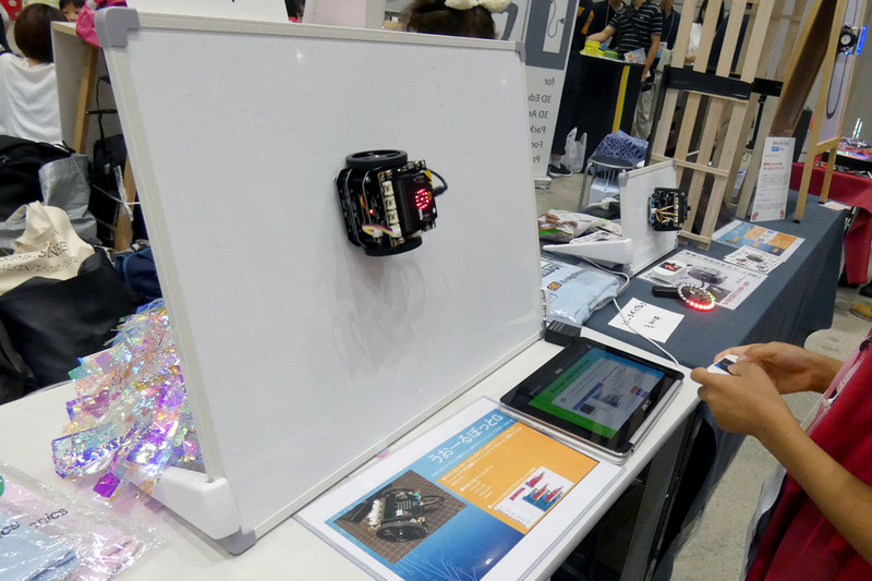 “じぇーけーそふとのこーなー”のブースでは、新型の「うおーるぼっとG」のデモが行われていた。うおーるぼっとは、磁力でホワイトボードなどの壁に貼り付いて動くロボットで、新型のGは、micro:bitを搭載できることが特徴だ