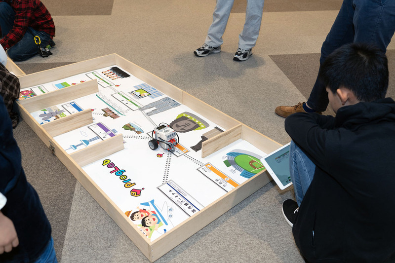 プログラボ、東京メトロ、JR中央ラインモールの共同ブースでは、レゴ マインドストームで組み立てたロボットを、線路のイラストに沿って進ませるプログラミングの講座を行なっていた