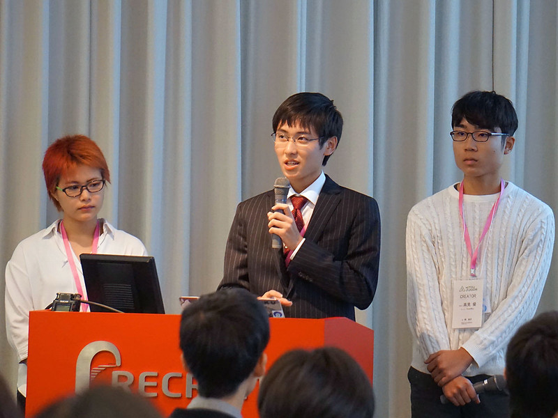 佐藤美咲さん（写真左）、末田貴一さん（写真中）、高見 優さん（写真右）は3名とも高等専門学校の3年生で、VRにおけるECの在り方を模索するプロトタイプ「TouchBuy」を発表した。さまざまな試行錯誤を繰り返した結果、VRで商品を売る時は、背景の作り込みが重要であること、リアル感のない商品の方が扱いやすいことに気づき、「VRおまもり専門店」を披露した。高校生だからこそ、収益化を気にすることなく、新しい分野に挑戦したかったと述べた