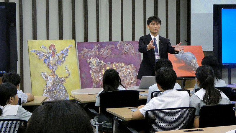 絵画を披露する鈴木教諭と近くで鑑賞する子どもたち