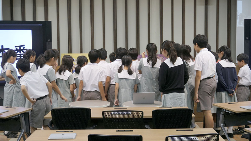 絵画を披露する鈴木教諭と近くで鑑賞する子どもたち