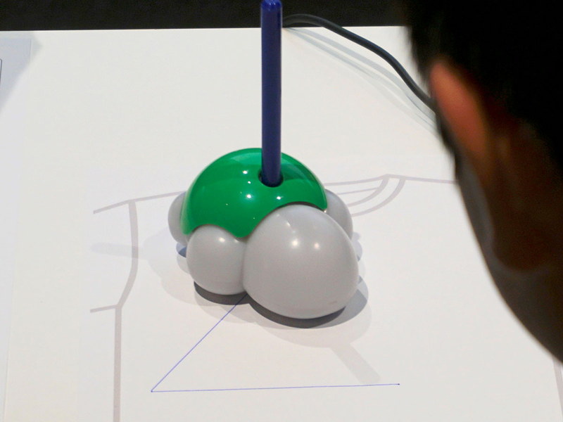 カメ型ロボットにペンを差し込み実際の紙に線を描いていく、画面内でやるよりも子どもたちは楽しそうだ