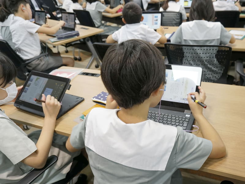 デジタル教科書の読み上げ機能とイヤホンを使って本文を確認する児童（2019年7月の公開授業セミナーより）