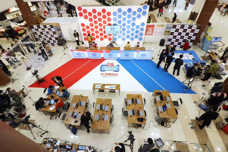 全国大会会場となったアリオ川口の吹き抜けスペースには、ステージの左右にドローンとロボットの制御系競技のエリア、手前に審査員と各チームの待機スペースを設置、その外側に選手の関係者の観覧席や、立ち見エリアが設けられた