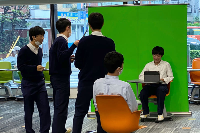 ワンポイント解説動画を作成中のようす。背景の板書とグリーンスクリーンの前で撮った解説動画を合成して仕上げる。「こういう学習は一人ひとり違うものができあがるのが面白い」と品田教諭