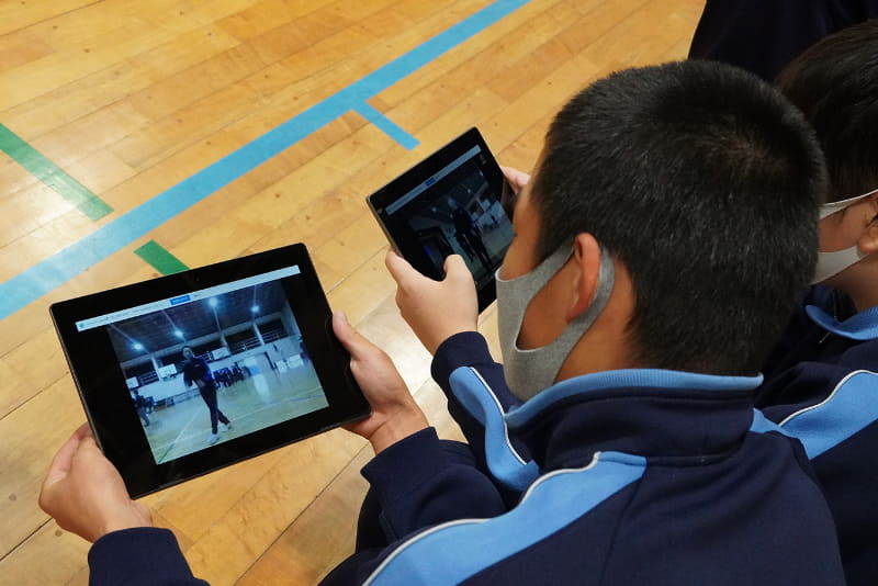 撮影した動画を友だちと見比べながら、互いの動きをアドバイスし合う生徒たち