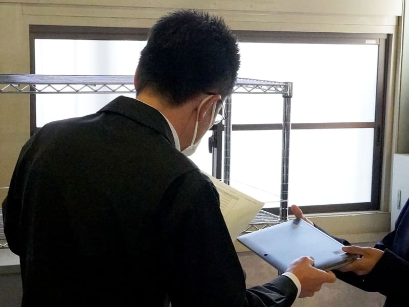 一列に並んで順番にタブレットPCを受け取る様子。教師は生徒一人ひとりの名前を確認しながら、耳元でパスワードを伝える