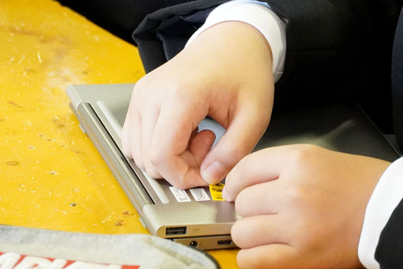 端末の3ヶ所に名前のシールを貼り、タブレットとキーボードの着脱を試す生徒たち