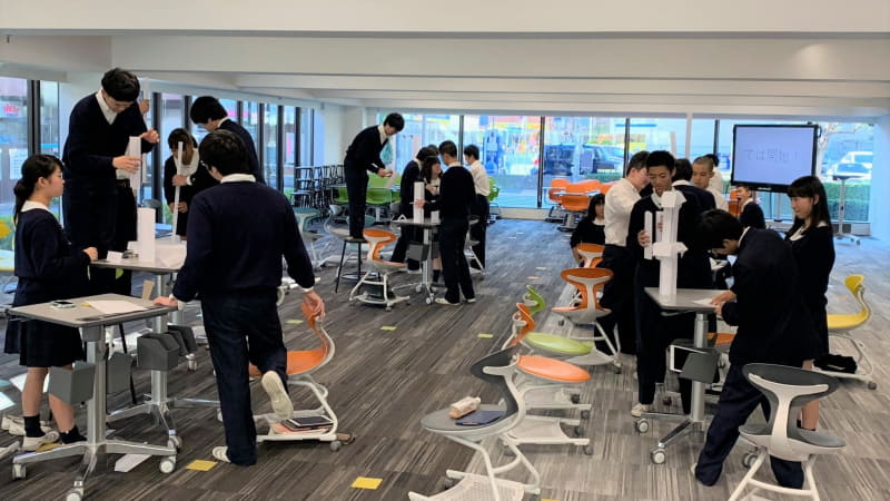 紙を積み上げて、てっぺんに消しゴムを載せる。制限時間内に高く作れたチームが勝ち