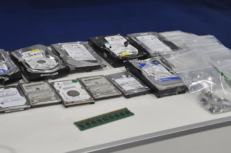 壊されたハードディスクが痛々しい、袋に入っているのは粉みじんにされたSSD