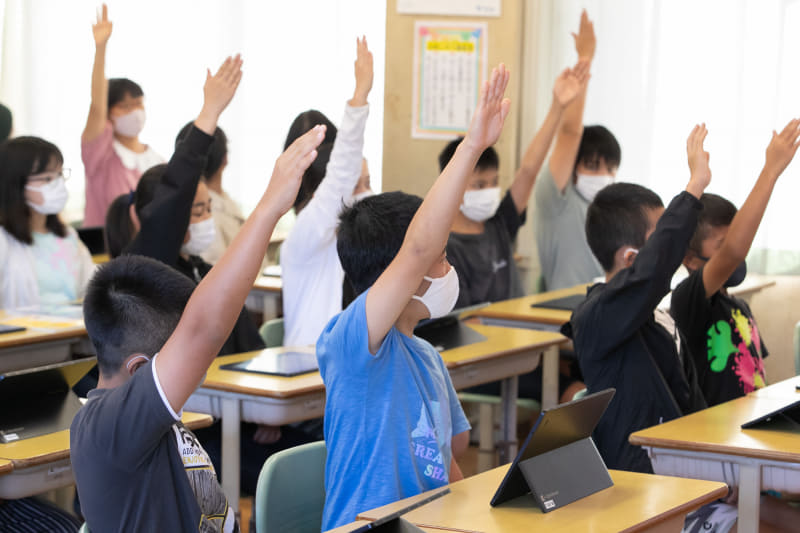 担任の問いかけに手をまっすぐ挙げて答える児童たち