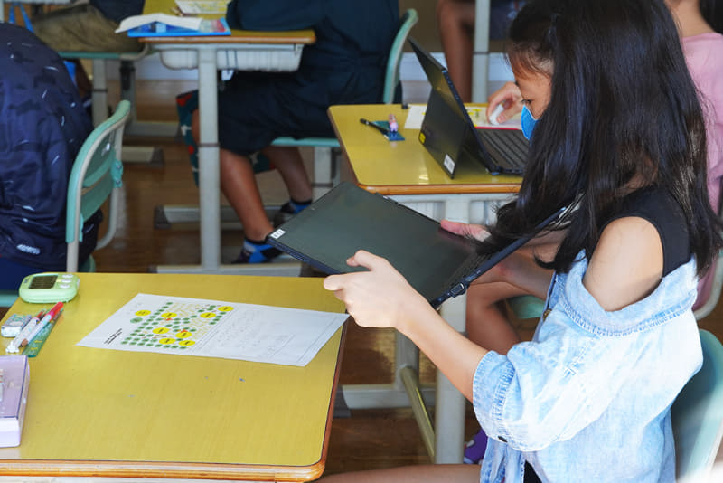 田んぼの米の収穫量を求める式をプリントに書いてタブレット端末で撮影。授業支援ソフトにアップして全体で共有