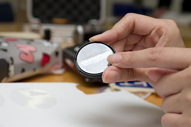 ロゴ入りレンズキャップを買ったときについている表面保護用のシール。これを捨てずに厚紙にペタッと貼ると型紙になる