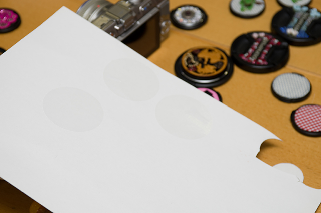 ロゴ入りレンズキャップを買ったときについている表面保護用のシール。これを捨てずに厚紙にペタッと貼ると型紙になる