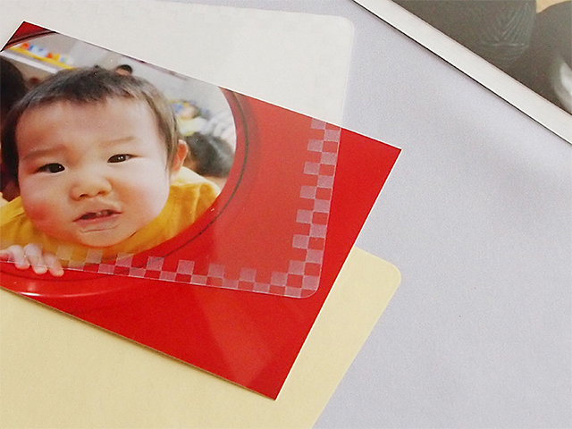 表フィルムの周囲にはチェックの模様入り。もともと入っている黄色の保護紙と写真を入れ替える