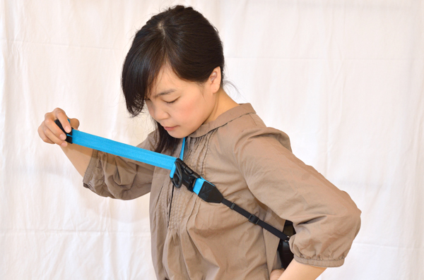 ロール状態のストラップ先端部分を引っ張り、カメラを背中に固定する