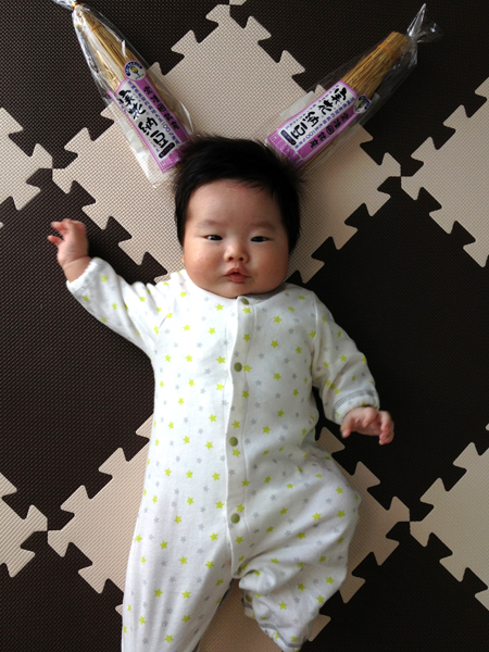 茨城のお土産「納豆」とパチリ。ワラに包まれている納豆をツノに見立てて頭の上に