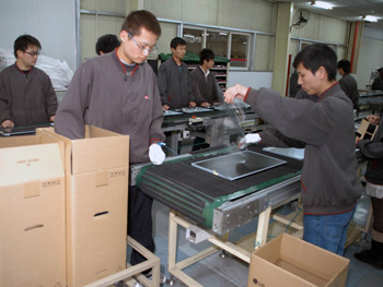 液晶パネルパーツをベルトコンベアに載せているライン最上流箇所