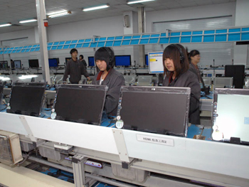 ヘッドフォン着用の工員はサウンド機能のチェックをしている